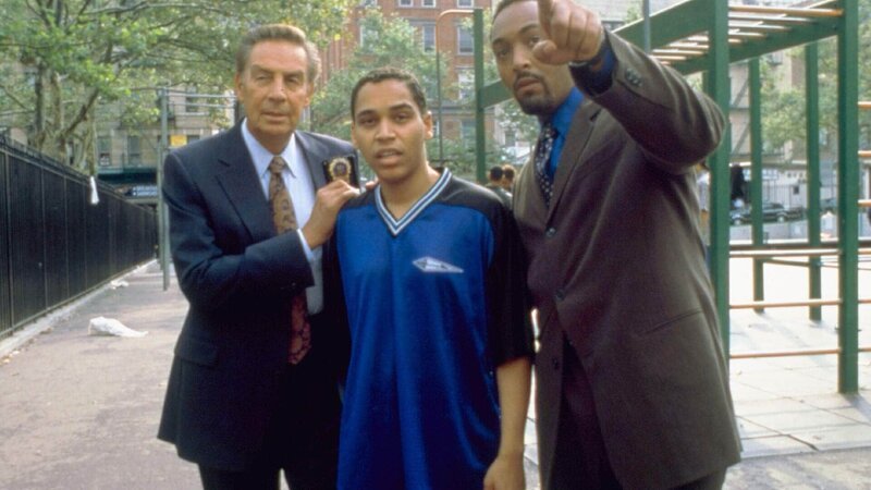 Detective Lennie Briscoe (Jerry Orbach, li.) und Detective Edward Green (Jesse L. Martin, re.) haben während eines Mordprozesse den Tipp bekommen, dass Nestor Salazar (Victor Anthony) den Mord als Mutprobe begangen haben soll. – Bild: RTL Deutschland