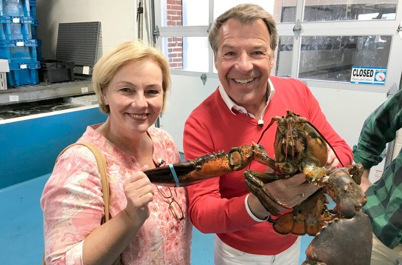 Schlagerstar Patrick Lindner und Kreuzfahrtdirektorin Manuela Bzdega mit einem neun Pfund schweren Lobster/​Hummer in einem Großhandel für die als Delikatesse geltenden Tiere in Boston, Massachusetts (USA). – Bild: BR/​Bewegte Zeiten GmbH/​Gerrit Mannes