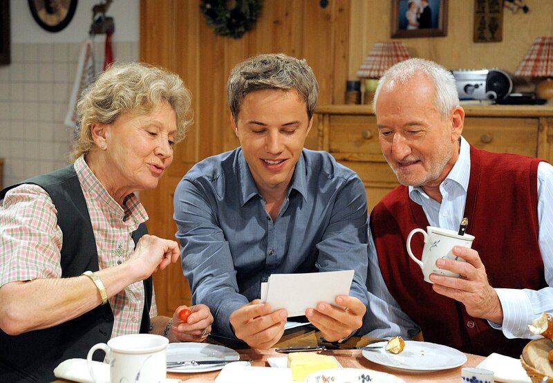 Martin (David Paryla, M.) präsentiert Hildegard (Antje Hagen, l.) und Alfons (Sepp Schauer, r.) Fotos seines Patenkindes. – Bild: ARD/​Jacqueline Krause-Burberg