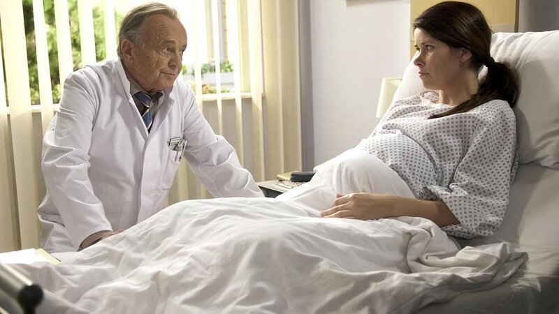 Prof. Simonis (Dieter Bellmann) Tochter Rebecca (Melanie Isakowitz) taucht unerwartet in der Sachsenklinik auf … und sie hat eine Überraschung dabei. Rebecca ist im fünften Monat schwanger. Vater und Tochter haben sich seit acht Jahren nicht gesehen und haben eine große Distanz zu überbrücken. Bei einer Routine-Untersuchung stellt sich heraus, dass sich bei dem Fötus ein sogenanntes amniotisches Band gebildet und um das Bein gelegt hat. Ohne Operation wird das Bein des Ungeborenen absterben. Da Rebecca Diabetikerin ist, besteht bei ihr ein erhöhtes OP-Risiko. – Bild: MDR/​Wernicke