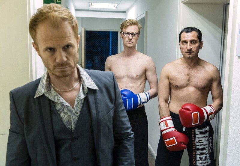 ARD HEITER BIS TÖDLICH – KOSLOWSKI & HAFERKAMP, neue Vorabendserie mit 16 Folgen, FOLGE 12, „Fliegende Fäuste“. Die Spur des toten Albaners Kreshnik führt Hasan Haferkamp (Tim Seyfi, r.) in einen Fight-Club. Um an den Boss des Clubs zu gelangen, tritt Hasan gegen den schlaksigen Simon (Eric Bouwer, M.) an und rechnet sich gute Chancen aus diesen zu besiegen (mit Komparse). – Bild: Sat.1 Emotions
