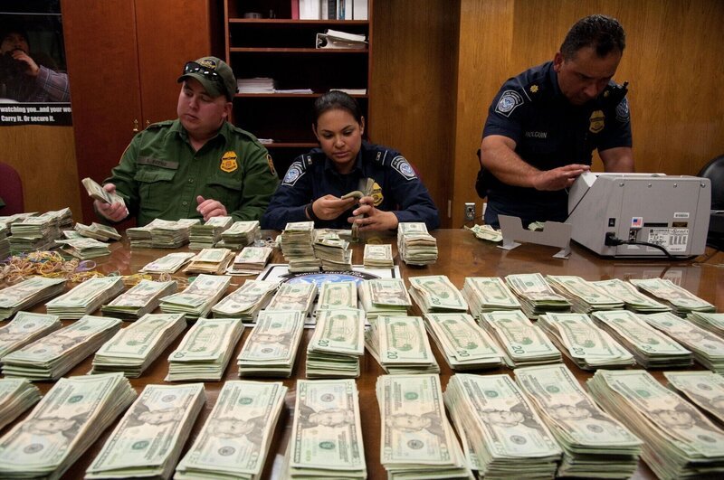 El Paso, TX: Two officers and an agent counting a large sum of confiscated cash. This cash seizure will put a dent in the powers of the cartel or gang of smugglers. The Border Protection agents remain alert for attempts to conduct illegal smuggling. – Bild: 2015 National Geographic Partners, LLC. All rights reserved. Lizenzbild frei