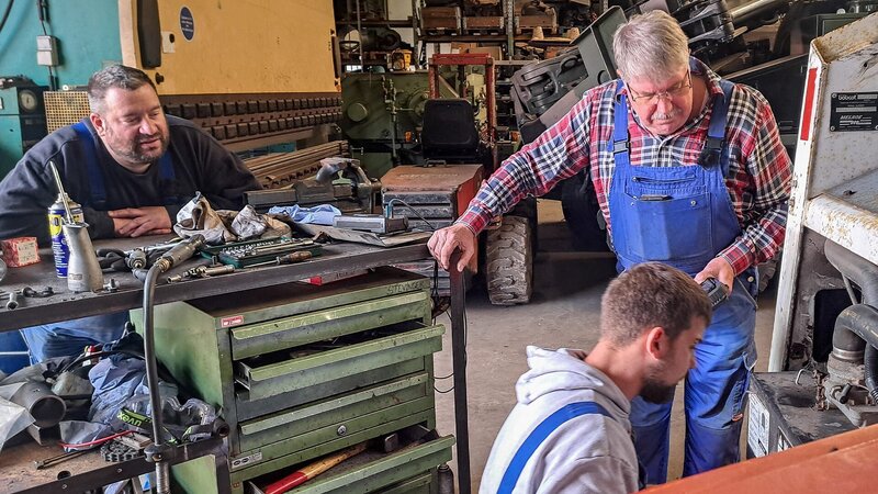 Mechaniker arbeiten an einem Bobcat 843. – Bild: DMAX