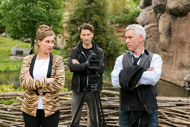 Zoodirektor Dr. Blum (Ralph Herforth, r.) und seine neue Mitarbeiterin Clara Baldin (Viola Pobitschka, l.) auf der vergeblichen Suche nach einem geeigneten Motiv für den neuen Imagefilm des Zoos. (im HG.: Moritz Heidelbach) – Bild: ARD/​Steffen Junghans