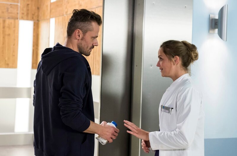 Eva (Sarina Radomski, r.) bittet Martin (Sven Waasner, l.), vor der Untersuchung nüchtern zu bleiben – auch Milch geht nicht. – Bild: ARD/​Jens Ulrich Koch