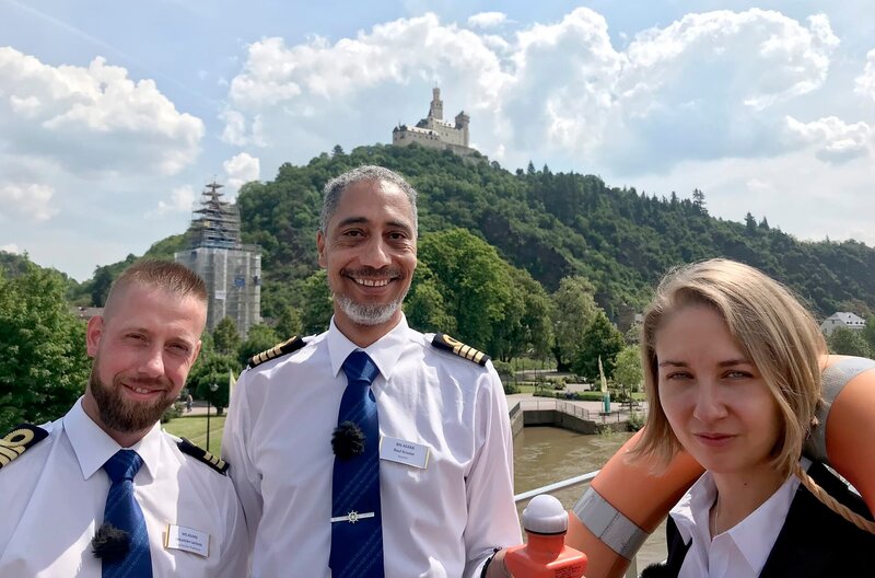 Kapitän Raul Kraaier und die Praktikanten Sebastian und Alexandra stehen vor der Marksburg in Braubach. – Bild: BR/​Bewegte Zeiten Filmproduktion/​Conny Schulze