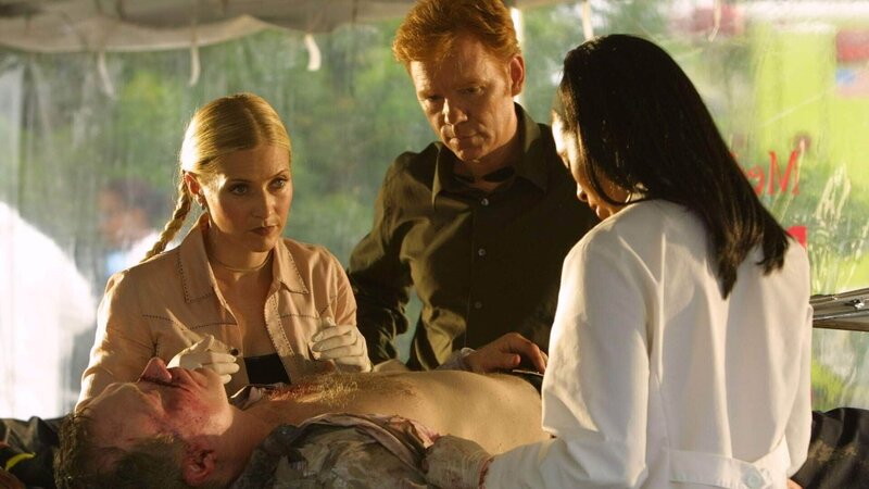 Die Gerichtsmedizinerin Alexx Woods (Khandi Alexander, r.) zeigt Calleigh (Emily Procter) und Horatio (David Caruso) eine Eintrittswunde in der Brust des Piloten. Wurde er erschossen? Wer hatte die Waffe mit an Bord? – Bild: SUPER RTL