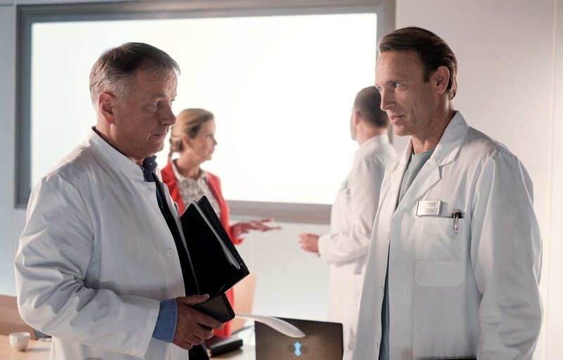 Nach Dr. Roland Heilmanns (Thomas Rühmann, li.) Rücktritt, muss eine Interimslösung für den Klinikleiterposten gefunden werden. Dr. Martin Stein (Bernhard Bettermann, re.) denkt, dass Chefarzt Dr. Kai Hoffmann (Julian Weigend, hi. re.) eine Möglichkeit wäre, in Zusammenarbeit mit Verwaltungschefin Sarah Marquardt (Alexa Maria Surholt, hi. li.). – Bild: MDR/​Saxonia Media/​Robert Strehler