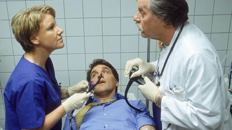 Dr. Schmidt (Walter Sittler, Mi.) hat sich in eine missliche Lage manövriert: Dr. Bender (Herbert Meurer, re.) und Nikola (Mariele Millowitsch) bereiten ihn für eine Magenspiegelung vor. – Bild: RTL /​ Guido Engels