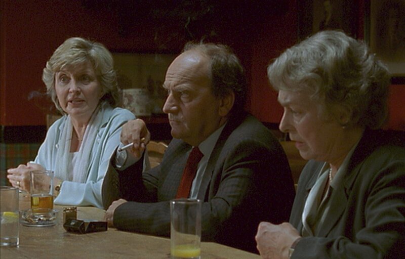 Bella Devere (Hannah Gordon, l.), der Metzger Ray Dorset (Bill Thomas, M.) und Peters Tante Barbara Drinkwater (Barbara Jefford, r.) beraten mit den anderen Mitgliedern des Festkomitees, wie es nach dem grausamen Mord mit der Teilnahme am Wettbewerb „Das perfekte Dorf“ weitergehen soll. – Bild: Honorarfrei