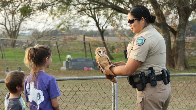 Warden Wei Wei Startz holding an owl and talking to kids. – Bild: Animal Planet /​ Discovery Communications, LLC