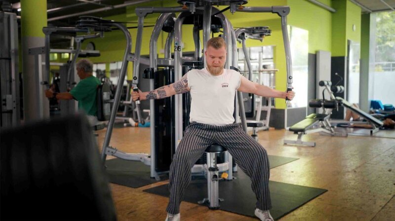 Beim Pumpen schlägt der Reflux zu: Sören L. macht regelmäßig Bodybuildung, wenn er sich an den Geräten ins Zeug legt, muss er immer wieder aufstoßen. – Bild: NDR/​Oliver Zydek