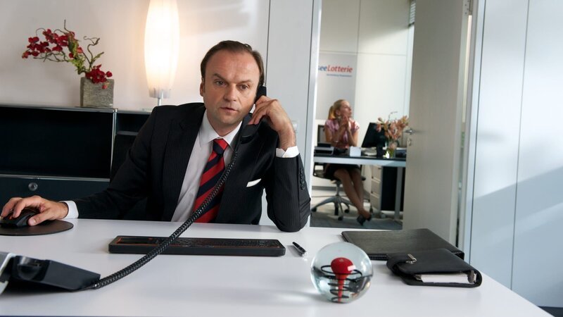 Der „Glücksbote“ der Lottozentrale gibt an, dass Maik seinen Lottoschein noch gar nicht eingelöst hat. – Bild: ZDF