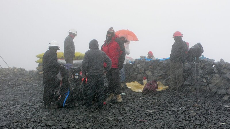 Filmteam und Goldminenarbeiter während eines überraschenden Schlechtwettereinbruchs vor der Mine Peru. – Bild: ORF