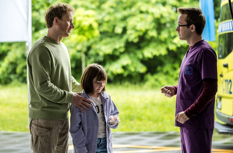 Assistenzarzt Oliver Probst (Arne Kertész, r.) nimmt die junge Patientin Maxine Liebig (M.) in der Notaufnahme auf, die von ihrem Vater Bjarne Liebig (Christian Sengewald, l.) begleitet wird. – Bild: ARD/​Saxonia Media/​Michael Kremer