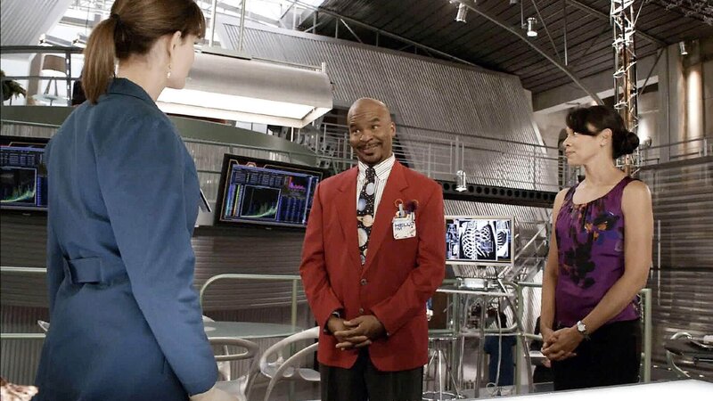 Obwohl Brennan (Emily Deschanel, l.) alle Hände voll zu tun hat, bringt Cam (Tamara Taylor) Professor Bunsen Jude (David Alan Grier), den Moderator einer Kinderwissenschaftsshow, zu ihr ins Jeffersonian. Er bittet Brennan, in seiner Sendung aufzutreten und bietet ihr einen Deal an … – Bild: TVNOW /​ FOX