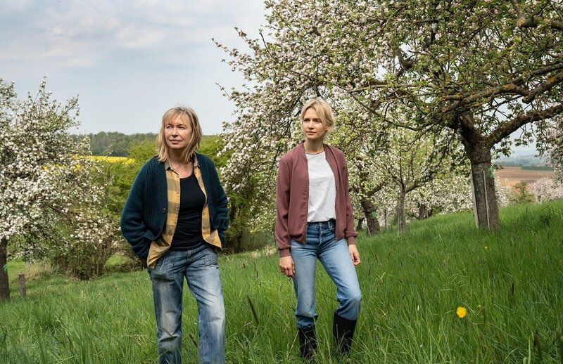 Frieda (Therese Hämer,l.) und Elli (Frida-Lovisa Hamann, r.) stehen in einer Obstplantage. – Bild: ZDF und Bettina Mueller