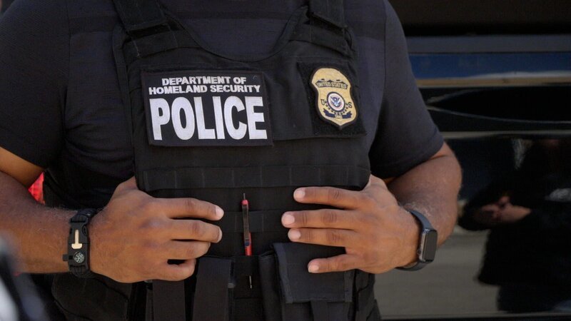 Ein HSI-Agent hält seine kugelsichere Weste während eines Briefings über eine bevorstehende Operation in Miami, Florida, fest (National Geographic) – Bild: National Geographic /​ Disney