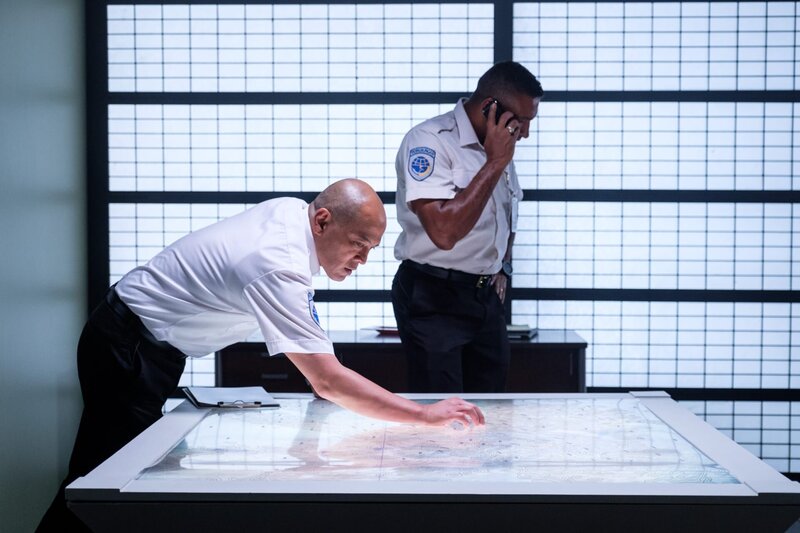 KNKT Investigators Ray Nurcahyo (played by Von Flores) reviews maps concerning the flightpath of Trigana Service Flight 267, while KNKT Investigator Ony Wibowo (played by Josh Barilko) receives a crucial call that might help them. – Bild: Darren Goldstein /​ Cineflix