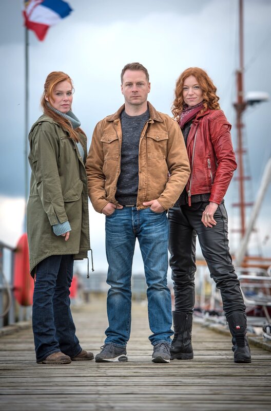 „Nord bei Nordwest – Der Transport“, Der legendäre ‚Nordic Ride‘ entlang der Ostseeküste zieht Biker aus aller Welt an. Für vier Schweden ist das Rennen aber nur ein Vorwand, um einen ganz großen Coup zu landen. Ein Transporter mit kostbaren Diamanten soll überfallen werden, während alle Aufmerksamkeit auf dem Rennspektakel ruht. Als einer der Gangster kurz vor Rennbeginn erschossen am Stand angespült wird, ist jedoch Polizistin Lona Vogts Misstrauen geweckt. Gemeinsam mit Ex-Cop Hauke Jacobs heftet sie sich an die Fersen der vermeintlich harmlosen Fremden.Im Bild (v.li.): Henny Reents (Lona Vogt), Hinnerk Schönemann (Hauke Jacobs), Marleen Lohse (Jule Christiansen). – Bild: NDR/​Degeto/​Gordon Timpen