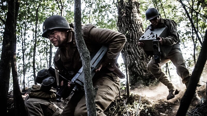 REENACTMENT- Leutnant Robert Weiss und Sgt. Ammon Sasser eilen mit Funkgeräten in der Hand an die Frontlinie. Gespielt von: Nathan Plumite (von links nach rechts), Kevin Trumble. – Bild: Liam Herring /​ Holdout II Productions Inc.