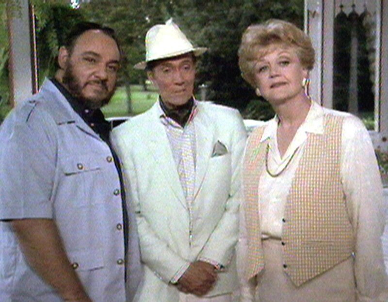 Jessica Fletcher (Angela Lansbury) ist zu Besuch bei ihrer Freundin Olivia auf Jamaika. Dort trifft sie auf Olivias Schwager Harry (John Rhys-Davies, li.) und dessen Nachbarn Jean-Pierre Dusant (Hurd Hatfield, mi.). – Bild: Warner TV Serie