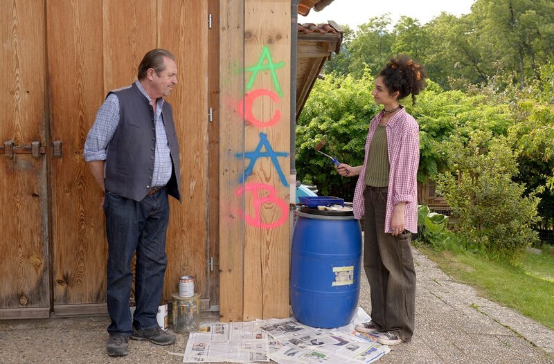 Getrieben von ihrem schlechten Gewissen überstreicht Ava (Eilin Aliza, r.) das Graffiti und bekommt unverhoffte Hilfe von Beissl (Andreas Giebel, l.). Gemeinsam überstreichen die beiden das Graffiti. Ihr Geburtstags-Zoff wird buchstäblich übertüncht! – Bild: ARD/​Rupert Scheele