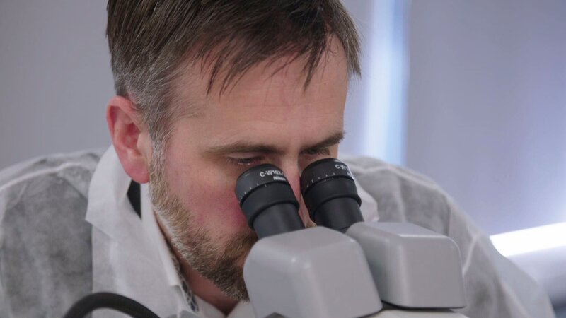 Ein Mann schaut durch ein Mikroskop – Bild: cinflx