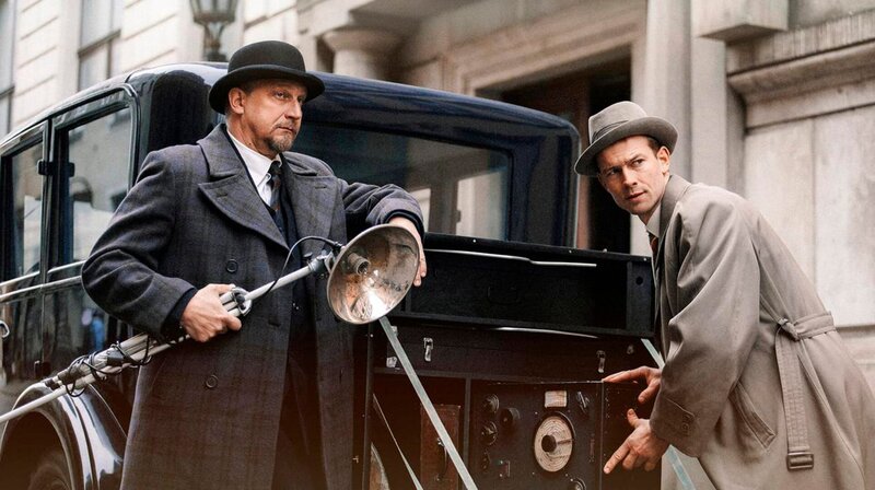 Die Kommissare Max Schreiber (Matthias Komm) und Fritz Kiehl (Christian Clauß) beim Beladen des sogenannten „Mordautos“. Im Wagen ist alles untergebracht, was die Ermittler für eine Tatortsicherung brauchen – vom Pinsel bis zur Fotoausrüstung. – Bild: phoenix/​ZDF