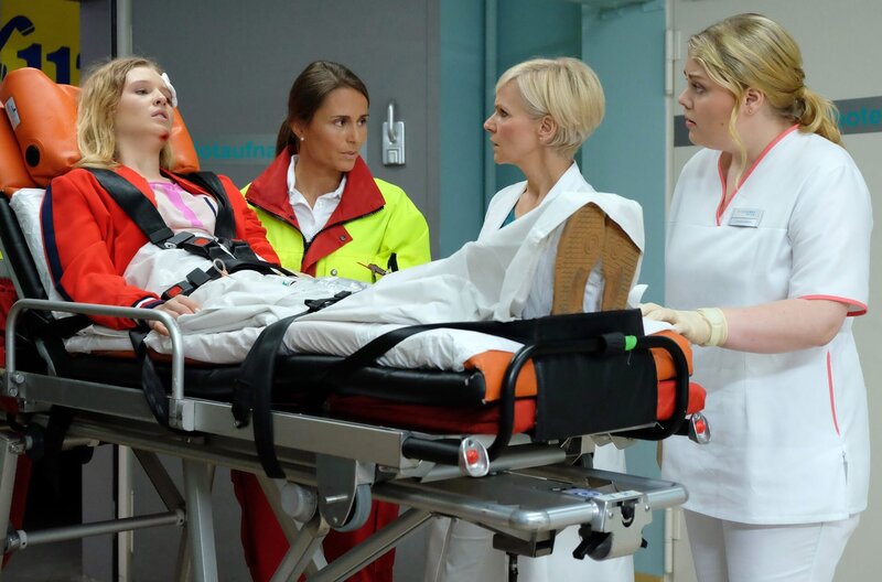 Dr. Kathrin Globisch (Andrea Kathrin Loewig, 2.v.re.) und Schwester Miriam (Christina Petersen, re.) nehmen erneut Sina Weigand (Lina Keller, li.) in der Sachsenklinik auf. Die Notärztin (Caren Seifert, 2.v.li.) gibt an, dass Sina wieder nur kurzzeitig bewusstlos war, doch dieses Mal hat sie sich am Kopf kleine Verletzungen zugezogen. – Bild: MDR/​Saxonia Media Filmproduktion/​Kiss