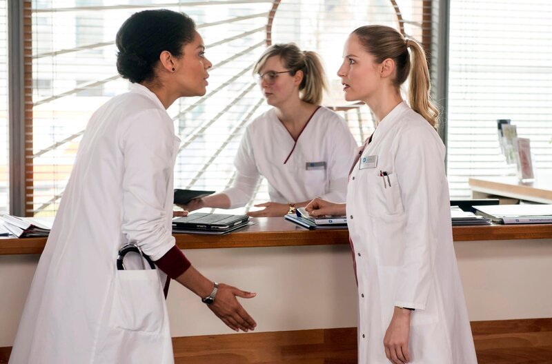 Vivi (Jane Chirwa, l. mit Komparsin, M.) und Julia (Mirka Pigulla, r.) geraten wegen des Ehepaars Schneider aneinander. – Bild: ARD/​Jens Ulrich Koch