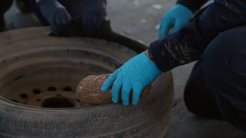 CBP-Beamter Gonzalez hält ein Paket mit mutmaßlichen Betäubungsmitteln in der Hand, nachdem er es aus dem Reifen des Fahrzeugs eines Verdächtigen in Miami, Florida, gezogen hat. – Bild: National Geographic