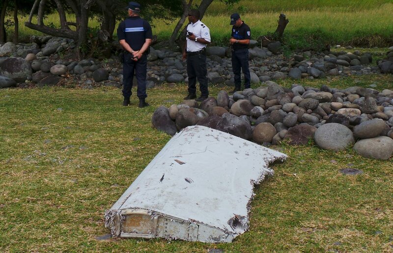French gendarmes and police stand near a large piece of plane debris which was found on the beach in Saint-Andre, on the French Indian Ocean island of La Reunion. France’s BEA air crash investigation agency said it was examining the debris, in coordination with Malaysian and Australian authorities, to determine whether it came from Malaysia Airlines Flight MH370, which vanished last year in one of the biggest mysteries in aviation history. – Bild: STRINGER/​FRANCE /​ Reuters /​ X01282 /​ Public Domain; Journal Del’Ile de la Reunion