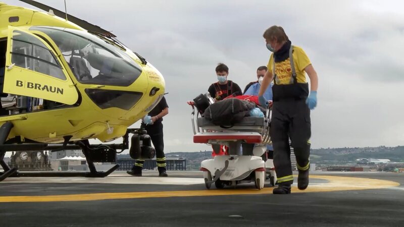 Paramedic Mikie pushing patient across helipad of Leeds General – Bild: DMAX