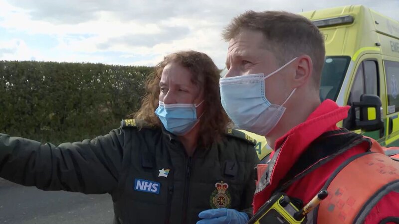 Paramedic Andy talking to ambulance staff at the scene of the accident – Bild: Warner Bros. Discovery, Inc. or its subsidiaries and affiliates.