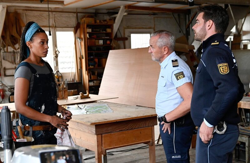 Ella Bartels (Sabrina Ceesay, l.), die Besitzerin einer Bootswerkstatt wird von Paul Schott (Tim Wilde, 2.v.r.) und Jakob Frings (Max König, r.) befragt. Auf einem ihrer Boote wurde Sprengstoff gefunden. – Bild: ORF/​Bavaria/​ARD/​SWR/​Laurent Trümper