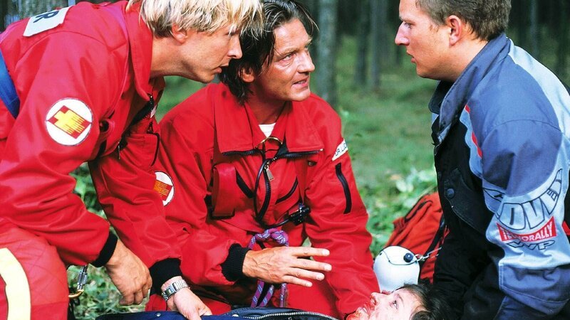 Peter (Serge Falck, l.) und Dr. Lüdwitz (Rainer Grenkowitz) bemühen sich, um die lebensgefährlich verletzte Kathrin (Julia Cencig) am Leben zu erhalten. Doch leider hat ihr Mann Bernd (Lars Pape) den Motoradhelm abgezogen, bevor das Rettungsteam vor Ort war … – Bild: RTL /​ Helene Waldner