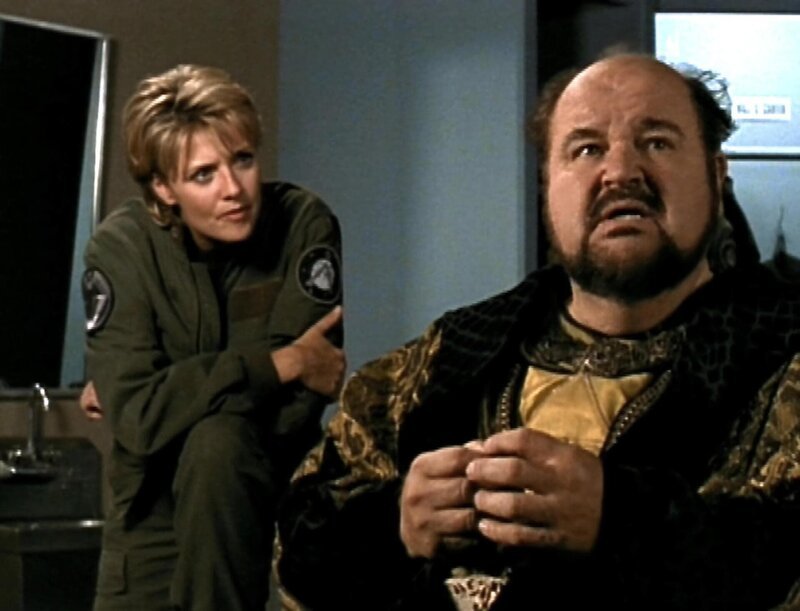Die SG-1-Mitglieder, darunter Dr. Carter (Amanda Tapping), sehen einen Mann namens Urgo (Dom DeLuise), bei dem es sich in Wirklichkeit um eine Projektion aus einem Mikrochip handelt … – Bild: RTL II