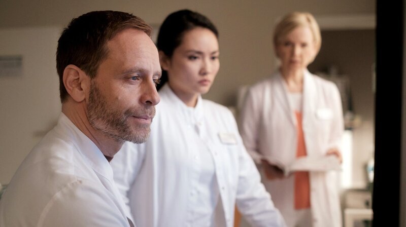 Dr. Kathrin Globisch (Andrea Kathrin Loewig, re.) hat einen Verdacht, was die Patientin von Dr. Lilly Phan (Mai Duong Kieu, mi.) haben könnte. Auch für Dr. Kai Hoffmann (Julian Weigend, li.) wäre das eine Erklärung. – Bild: MDR/​Saxonia Media/​Robert Strehler