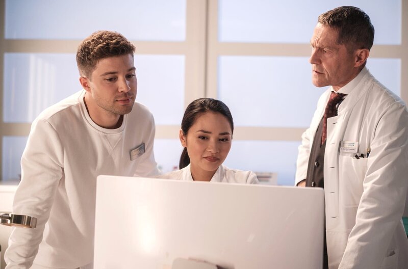 Dr. Kaminski (Udo Schenk, re.) will Kris Haas (Jascha Rust, li.) beweisen, dass es einen neurologischen Grund für die hanebüchene Geschichte eines Patienten gibt. Doch Dr. Lilly Phan (Mai Duong Kieu, mi.) kann keine neurologische Ursache finden. – Bild: MDR/​Saxonia Media/​Robert Strehler