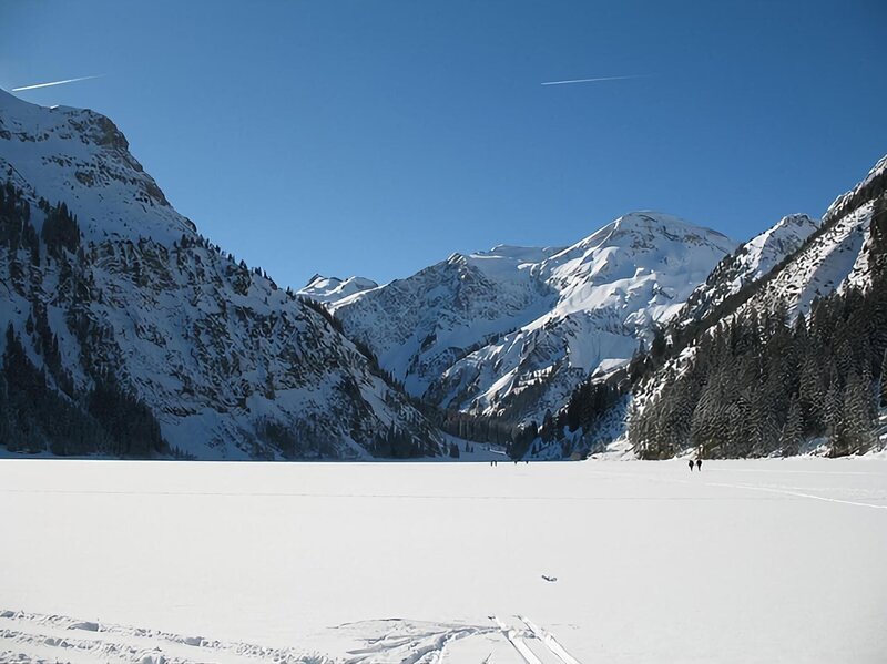 Im Winter ist der See dick zugefroren, so dass Skiläufer und Wanderer über ihn hinweg laufen. – Bild: Honorarfrei lediglich für Ankündigungen und Veröffentlichungen im Zusammenhang mit obiger BR-Sendung bei Nennung: Bild: BR/​Christina Moser.