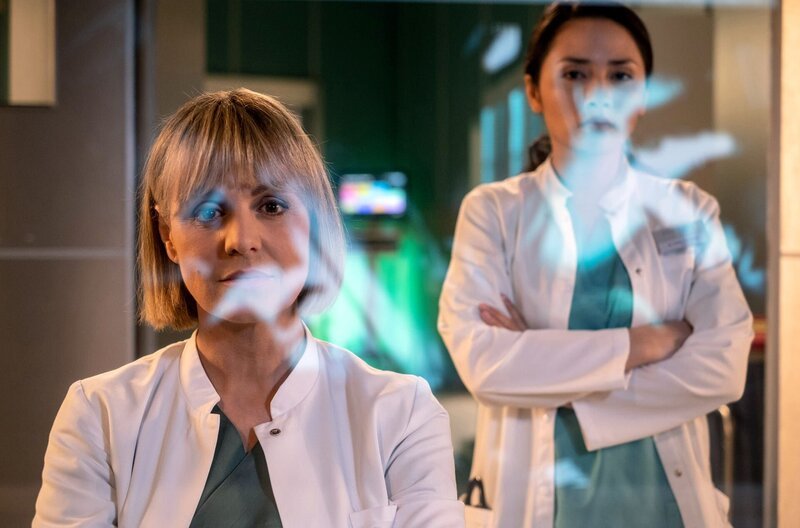Dr. Lea Peters (Anja Nejarri, li.) sieht sich den Verlauf der OP an und stellt fest, dass Dr. Lilly Phan (Mai Duong Kieu, re.) absolut alles richtig gemacht hat. Doch nach wie vor, ist Dr. Phan nicht mit der hochriskanten Bypass-OP einverstanden, die Dr. Peters vorschlagen will. – Bild: MDR/​Saxonia Media/​Robert Strehler