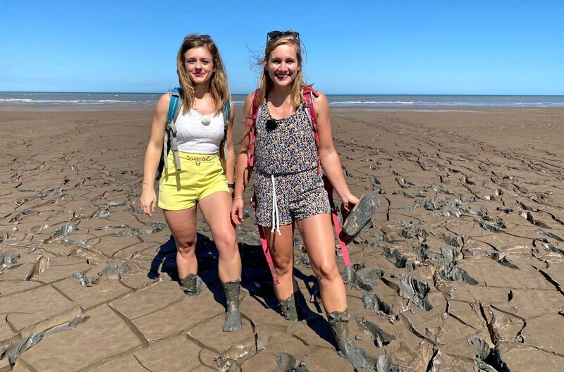 Rio Grande do Sul in Brasilien. Ausflug zum Cassino Beach – dem längsten Strand der Welt mit den Passagierinnen Lisa Forster und Christine Spindler (links). Zur Überraschung der beiden finden sie dort keinen weißen Sand, sondern dunkelbraunen Schlick, in dem sie knietief versinken. Die unverhoffte Wattwanderung macht den beiden riesen Spaß – doch dann pfeift die Beachwatch, die Flut kommt! Christine und Lisa müssen schnell raus aus dem Matsch. – Bild: BR/​Bewegte Zeiten Filmproduktion GmbH/​Cornelia Schulze
