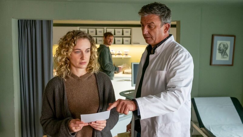 Dr. Martin Gruber (Hans Sigl, r.) hat für seine Patientin Jana Weiss (Pia Barucki, l.) gute Nachrichten: Sie ist schwanger. Doch ihre Freude ist verhalten, was auch David Ka?stner (Fre?de?ric Brossier, M.) irritiert. – Bild: ZDF und Erika Hauri