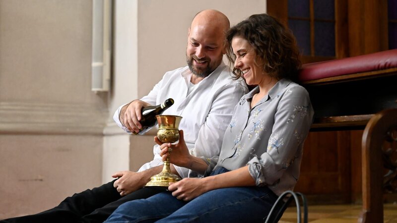 Parrer Reiser (Stephan Zinner) und Lisa (Anne Schäfer) trinken Wein und reden. – Bild: BR/​ORF/​maze pictures GmbH/​Barbara Bauriedl