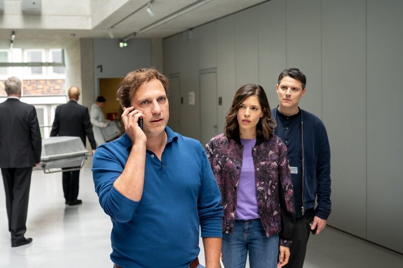 Die Kriminalkommissare Lea Gomez (Jasmin Gassmann) und Rico Sander (Benjamin Strecker, r.) ermitteln im Tötungsdelikt an einer renommierten Psychologin. Sie war an der Entwicklung eines revolutionären Forschungsprojekts involviert. Der Firmeninhaber Alexander Lindner (Alexander Weise, l.) zeigt sich schockiert über den Tod seiner Mitarbeiterin, doch die Ermittlungen bringen gravierende Unstimmigkeiten innerhalb des Forschungsunternehmens ans Licht. (Komparsen im Bild) – Bild: ZDF