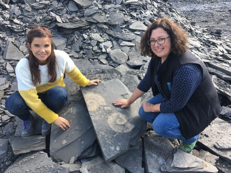 Auf einem Schieferbruch klopft Anna (links) mit Geologin Iris nach Fossilien. Sie finden zwei große Ammoniten. – Bild: BR/​TEXT + BILD Medienproduktion GmbH & Co. KG/​Ben Wolter