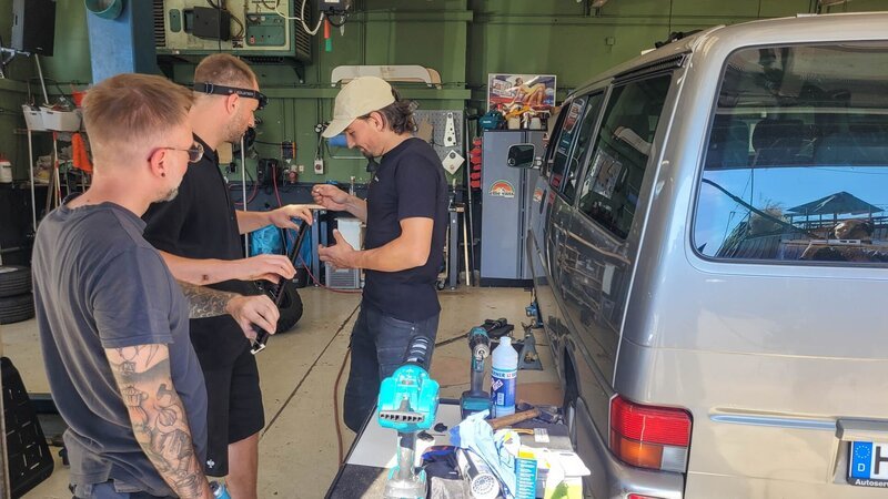 Drei Personen in einer Kfz-Werkstatt – Bild: Warner Bros. Discovery, Inc.