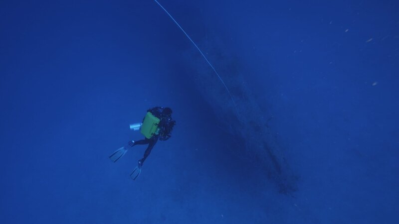 Taucher untersuchen die geschmolzenen und zerknitterten Überreste des Rumpfes der USS Gilliam. (National Geographic/​Andrew Fock) – Bild: Dan Stevenson /​ National Geographic