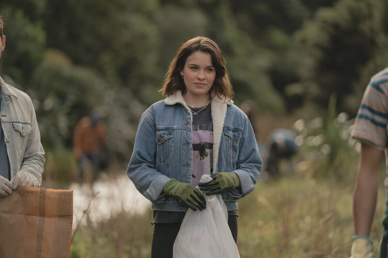 Issie (Macey Chipping) hilft bei der Müllsammelaktion. Seitdem Touristen die Wildpferdherde sehen möchten, leidet die Wildnis von Kauri Point. – Bild: ZDF/​Libertine Pictures Limited/​Slim Film/​ Television Limited